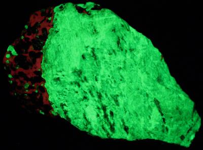 Pink willemite with calcite and franklinite, from the Sterling Hill Mine NJ. under shortwave UV Light