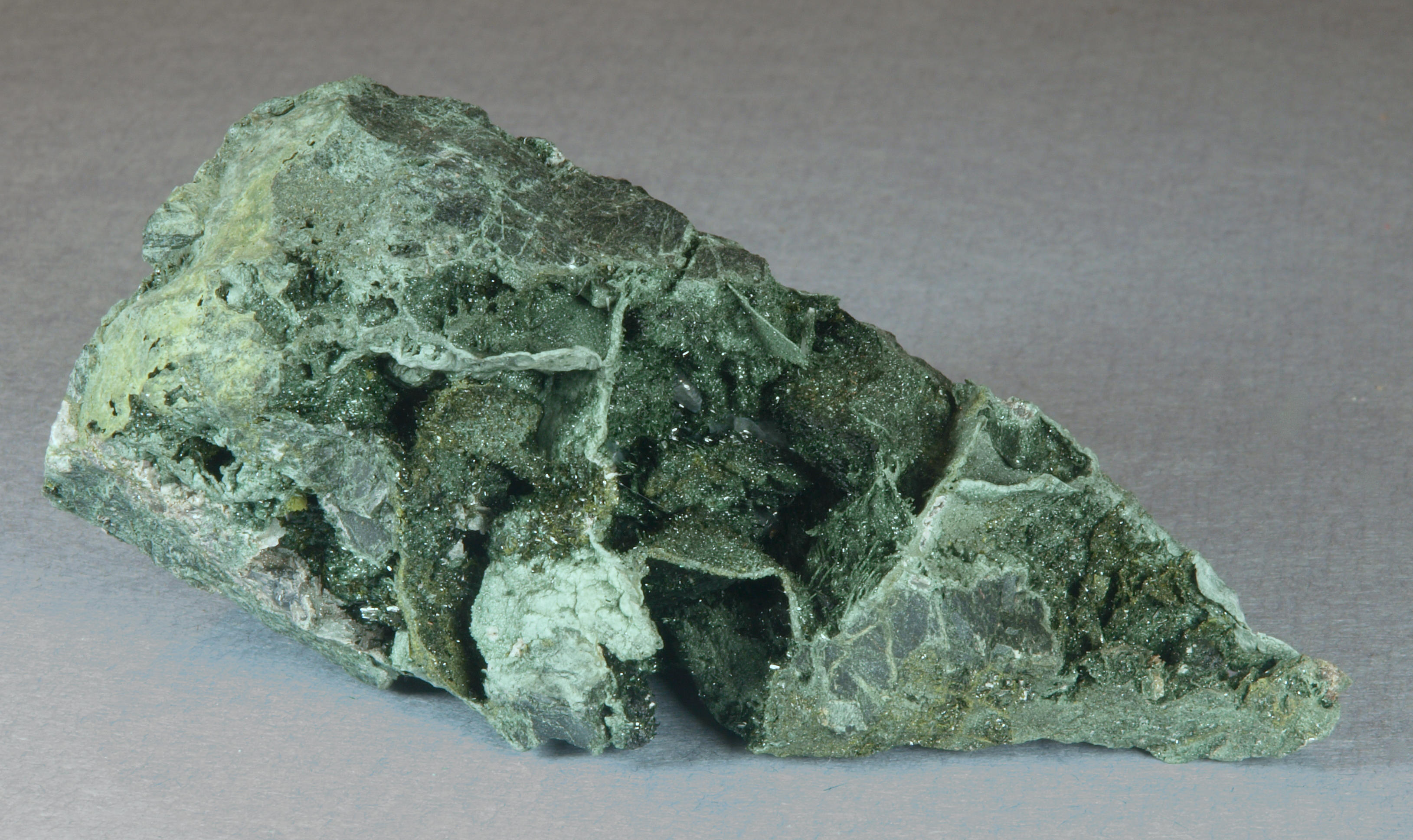 Tiny, dark green, acicular actinolite crystals, locally with equally tiny, brownish-green epidote crystals