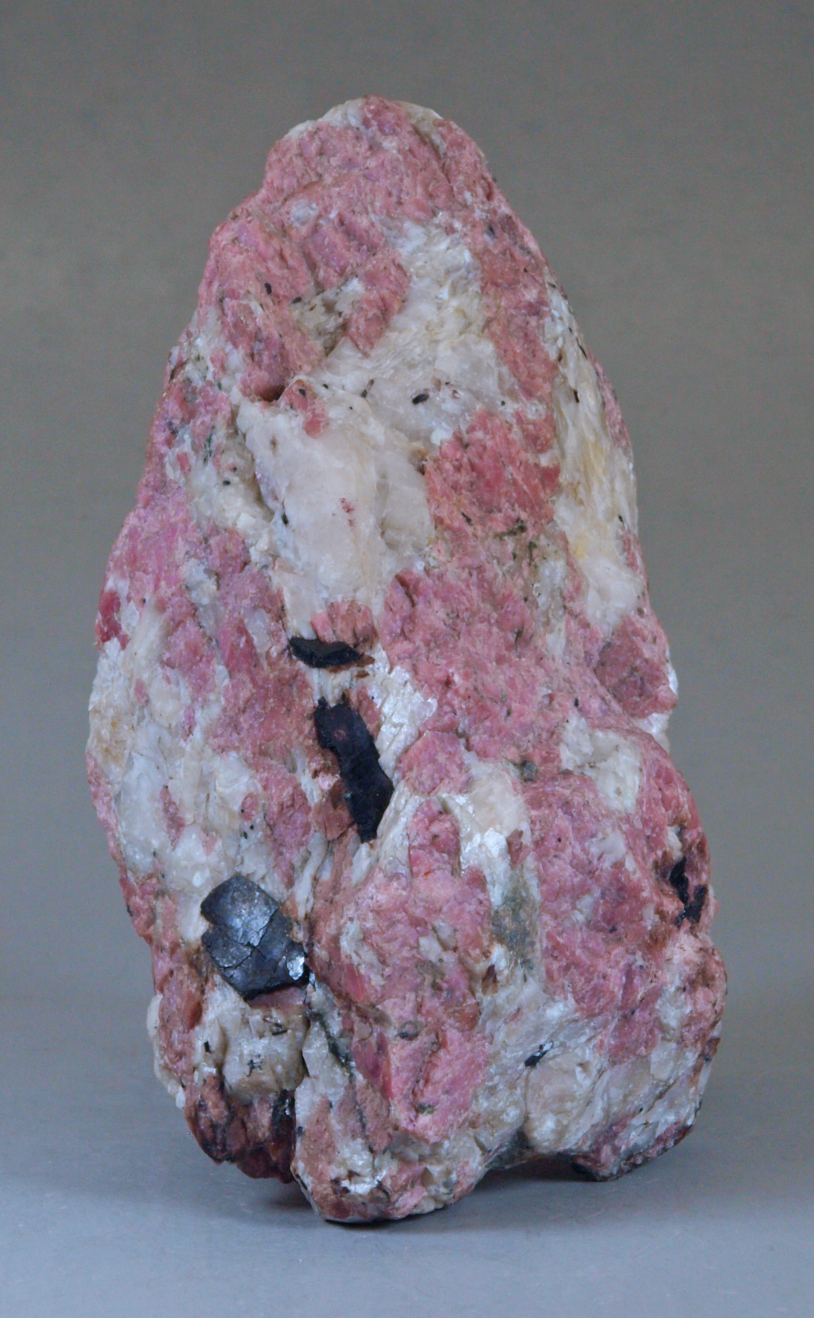 Black, bladed crystals of allanite in a coarse-grained matrix of pink rhodonite, bone-white calcite 