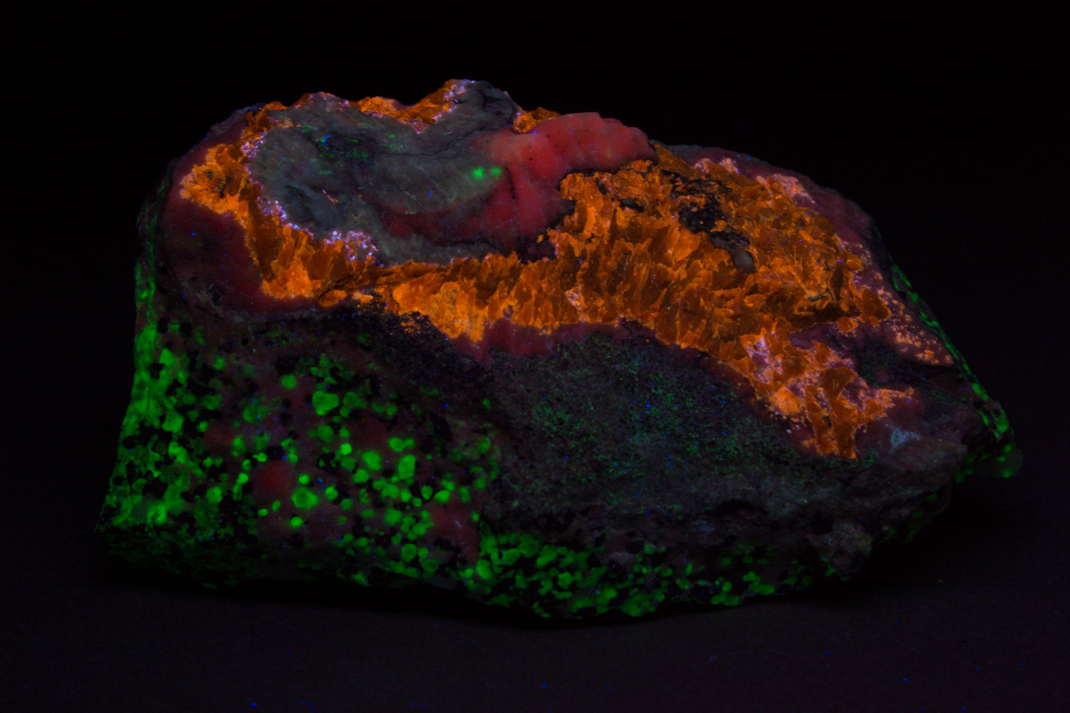 Faintly pink gerstmannite, white calcite, massive brown sphalerite, granular willemite-franklinite-calcite ore under longwave UV Light