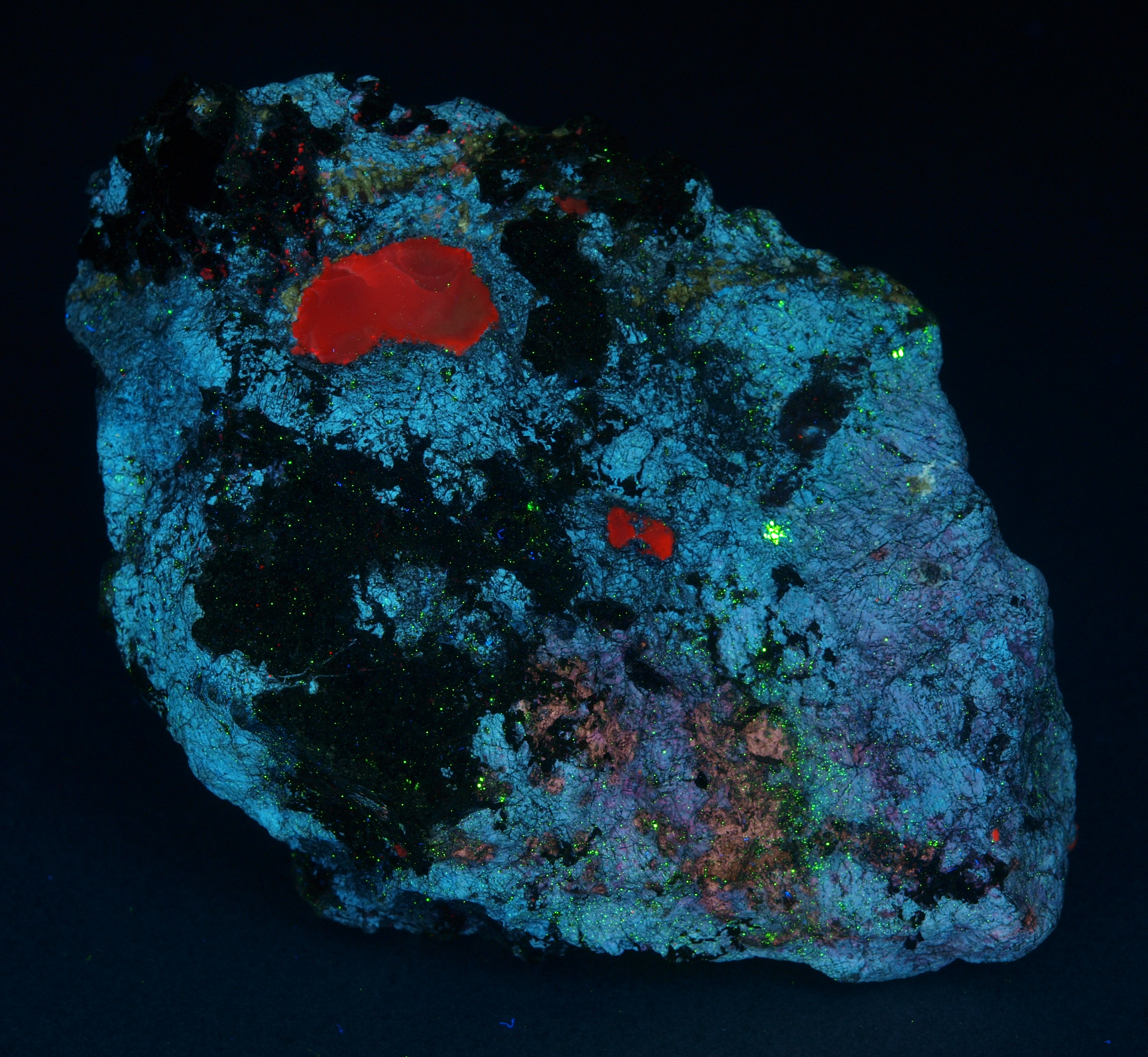 Gypsum, white roeblingite, massive brown andradite, franklinite, brown plates of hendricksite under shortwave UV Light
