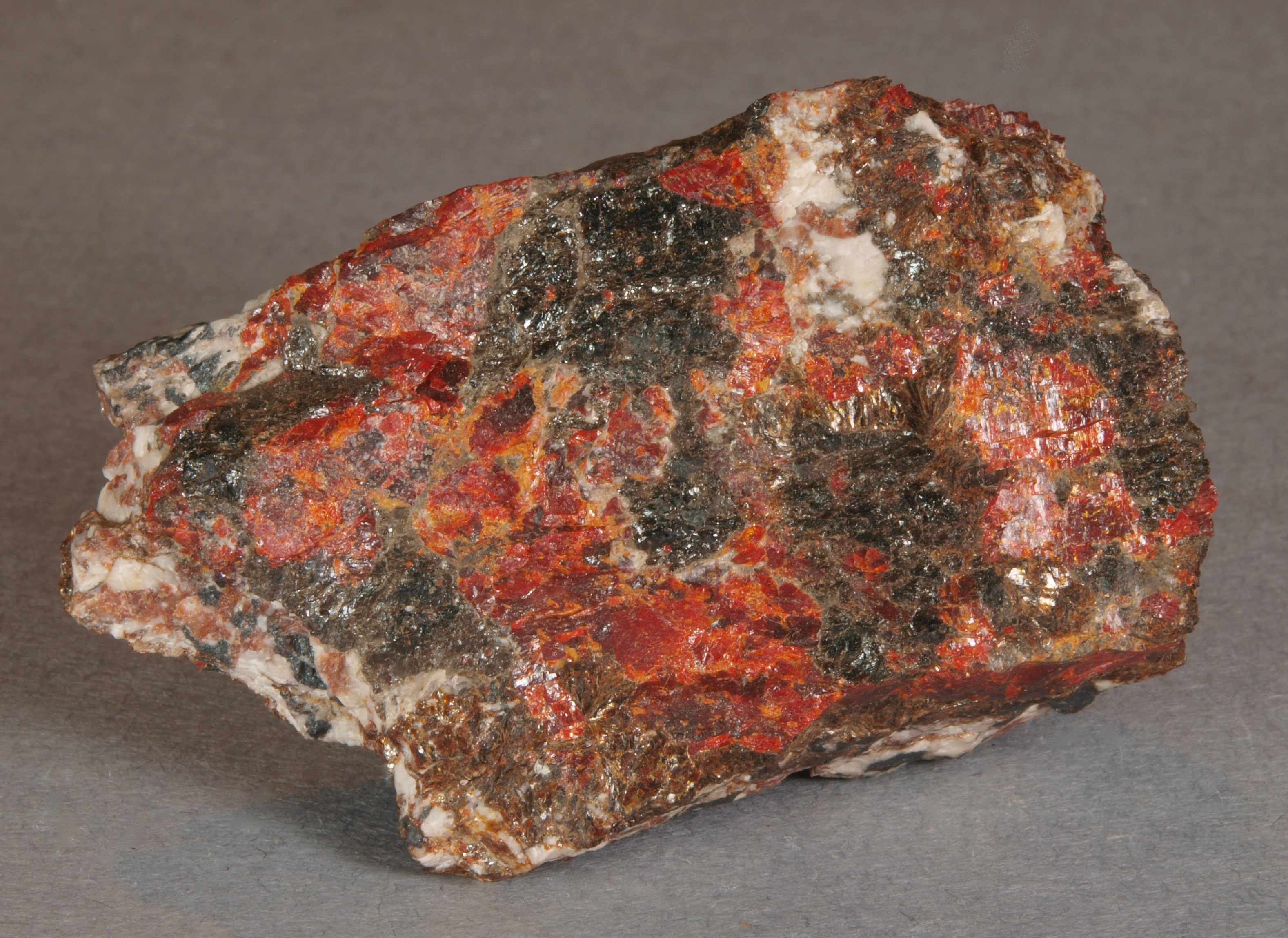 Assemblage of glassy, dark brown magnussonite with bright orange-red zincite